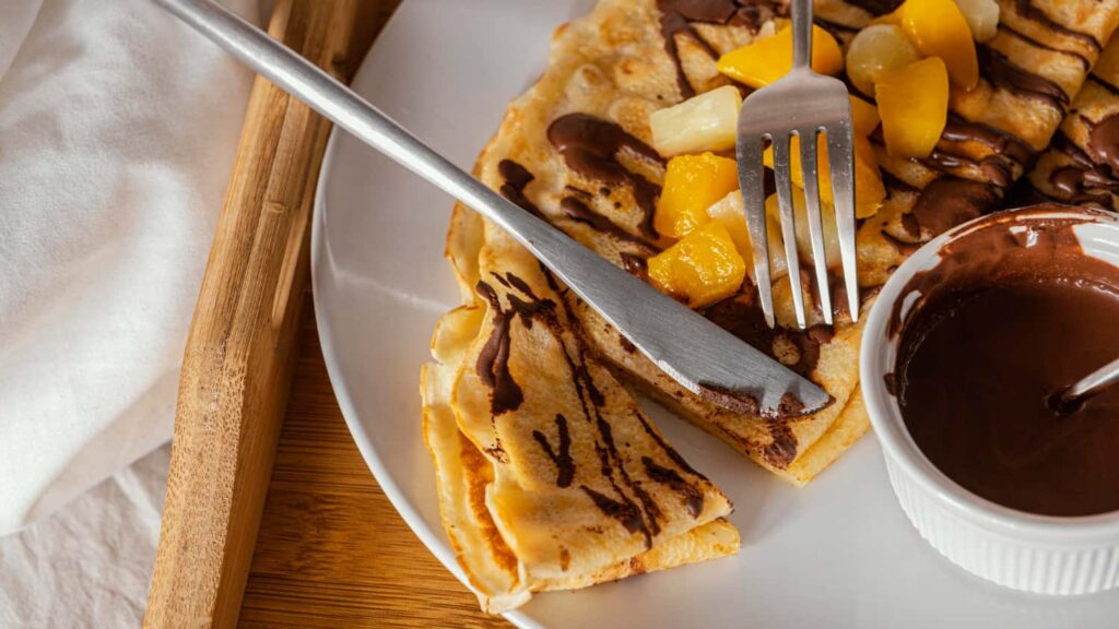 Crepes frías con sirope de chocolate y cubiertos